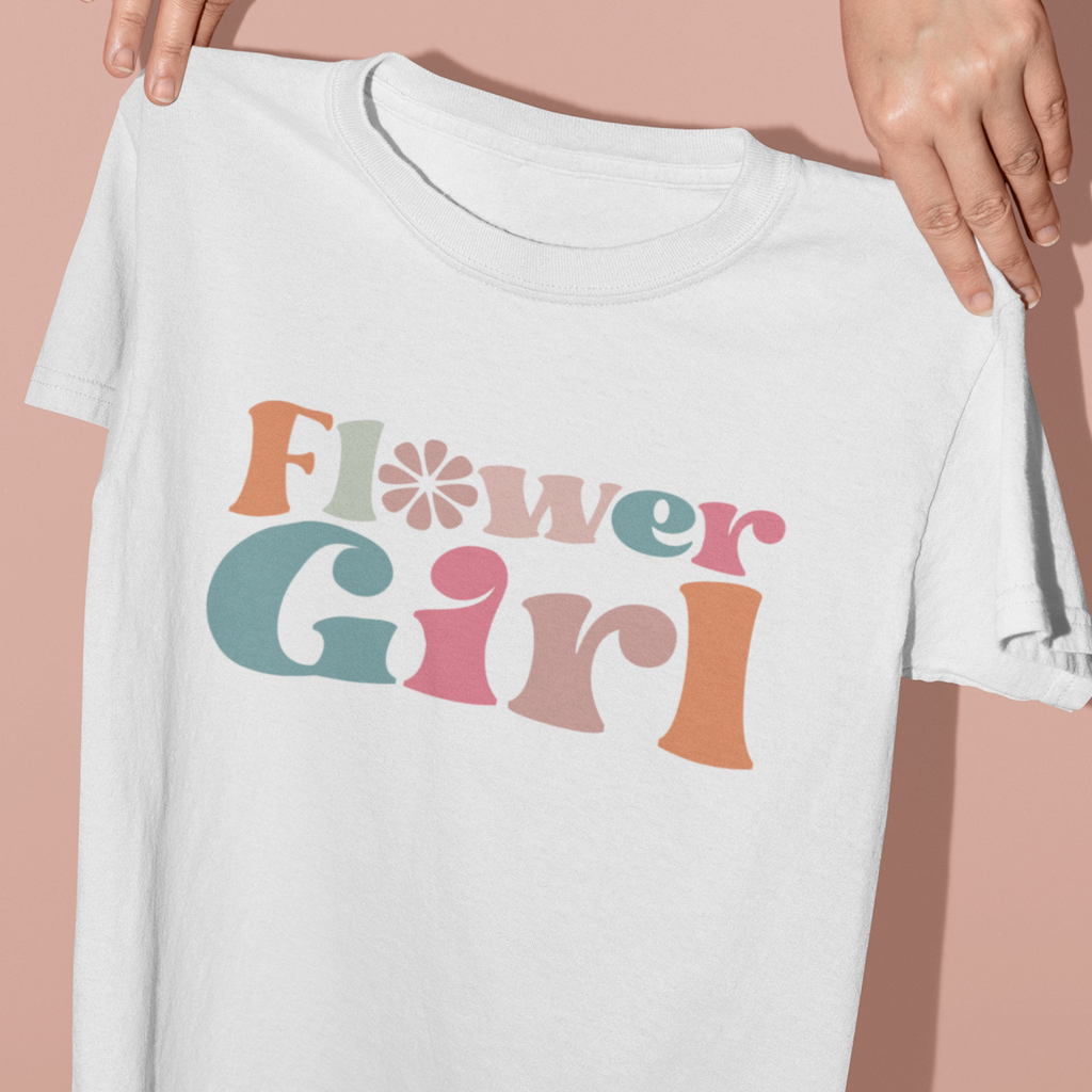 A white t shirt with "flower girl"written in retro pastel letters.