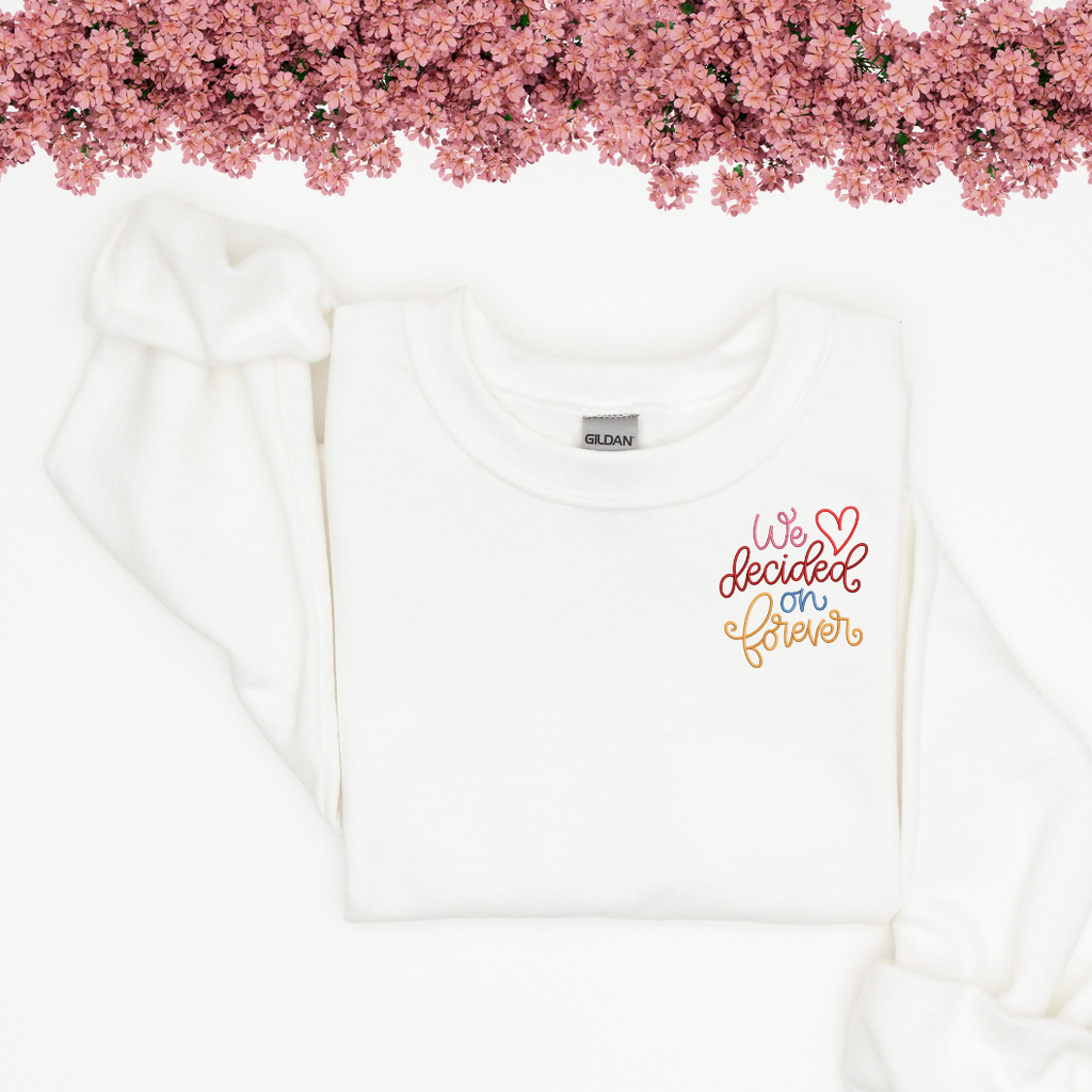 White crewneck with "we decided on forever" embroidered in the corner.