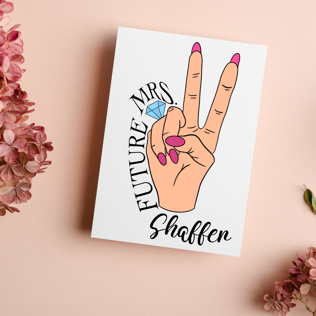 A personalized card, peace sign with a hand and pink nails with a ring on the fourth finger. A blush background with florals. Future Mrs Shaffer is written around the hand. A great personalized engagement gift for the newlywed.
