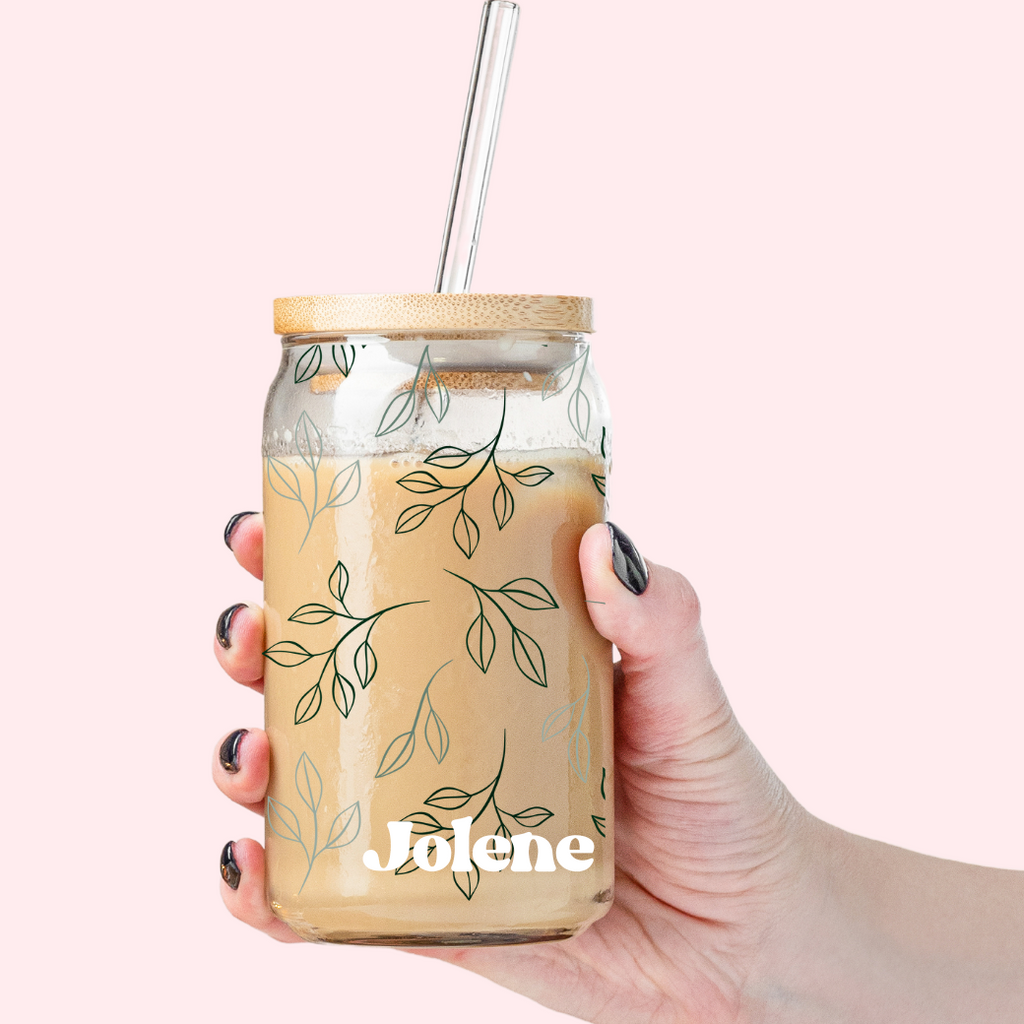 Glass tumbler with straw with a leafy design and "Jolene" written in white