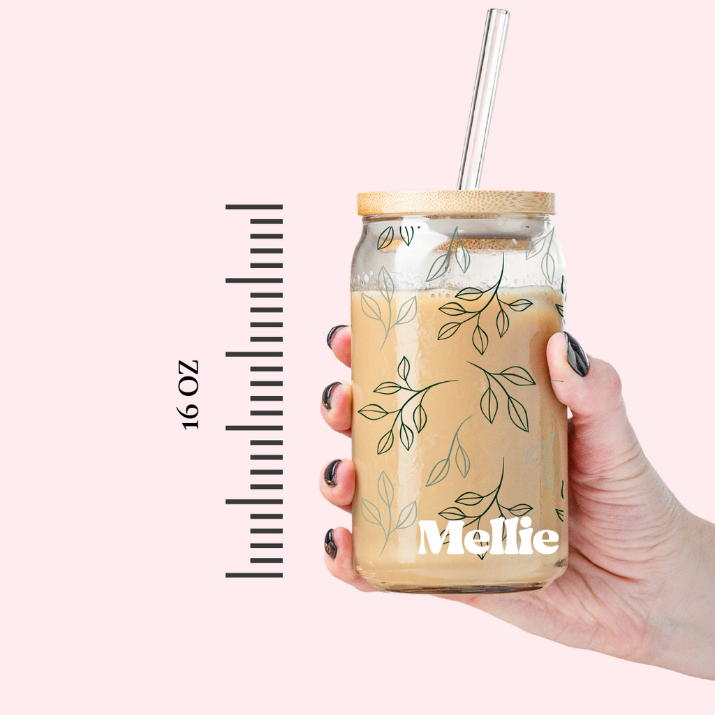 Glass tumbler with straw with a leafy design and "Mellie" written in white