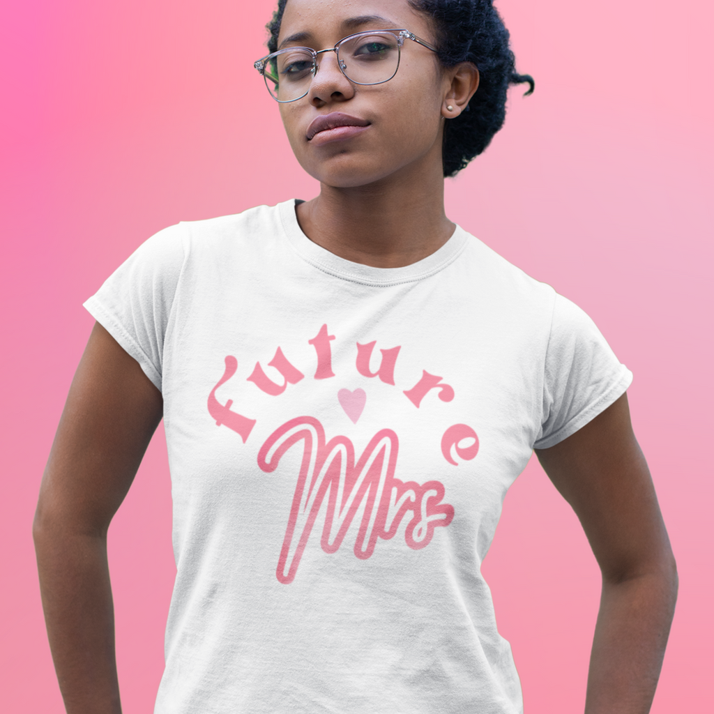 White T shirt with "Future <3 Mrs" written on the front. Worn by a woman on a pink background. The perfect gift for the bride!