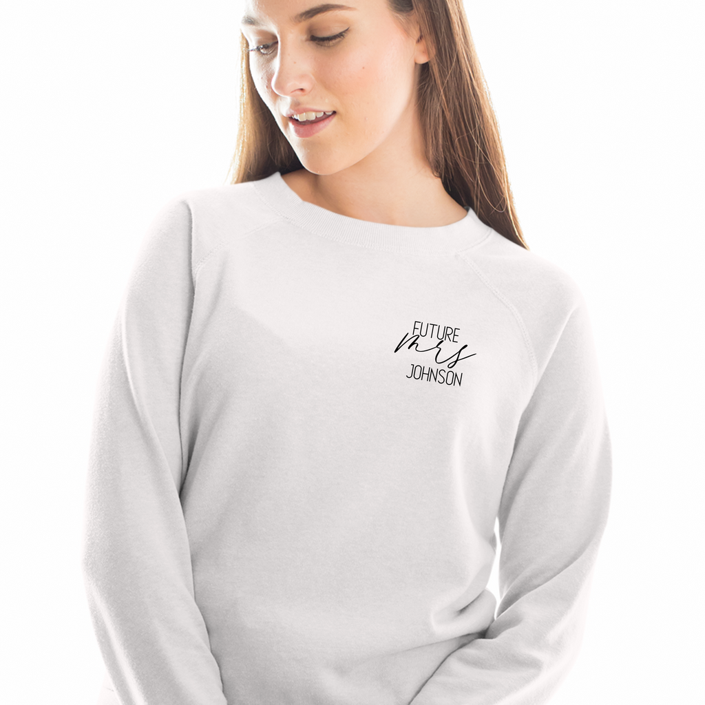 A white crewneck with "future mrs johnson" written on it. Worn by a woman on a white background.