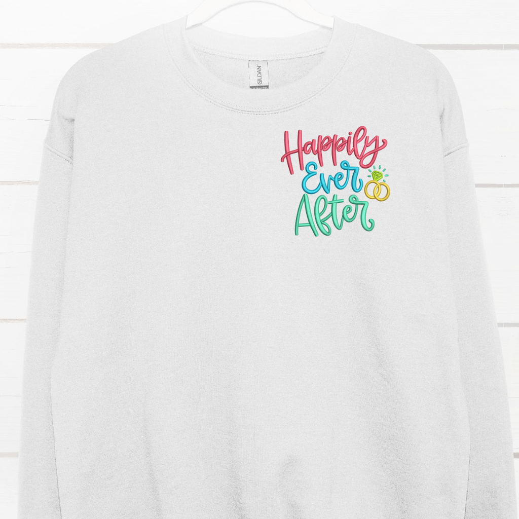White crewneck with "happily ever after" embroidered in the left corner in pink, blue and green.