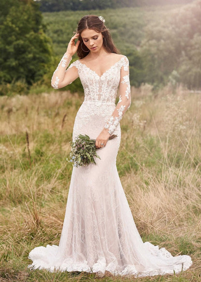 Woman wearing a long sleeve lace wedding dress holding a bouquet
