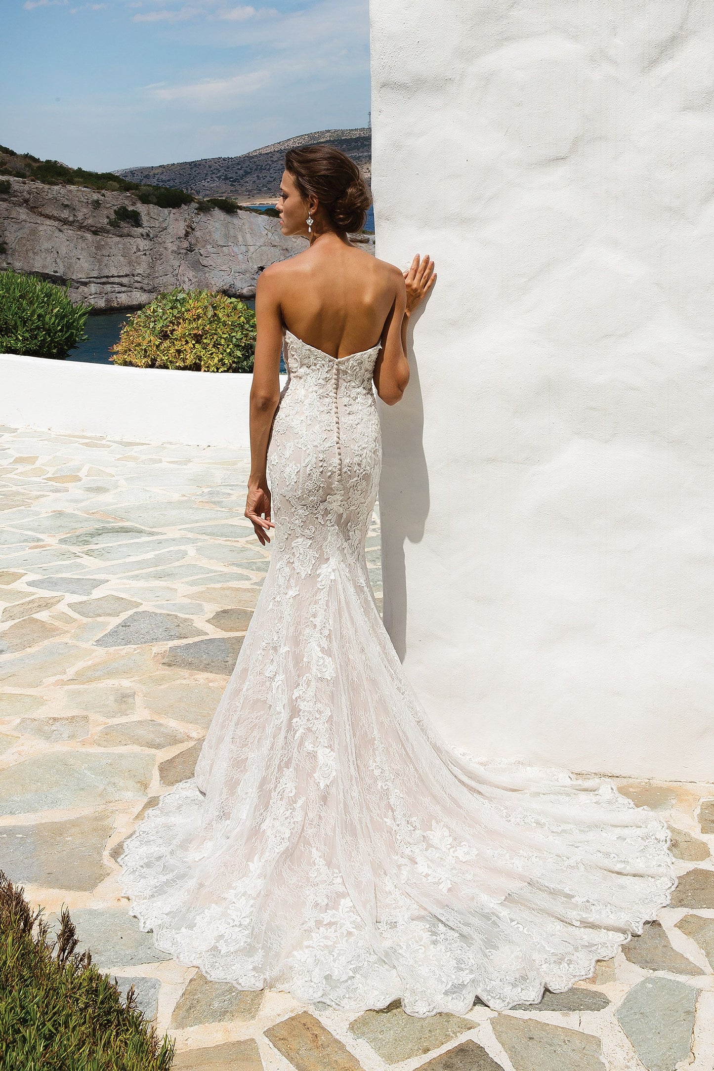 Young woman wearing a full lace wedding dress, strapless back view
