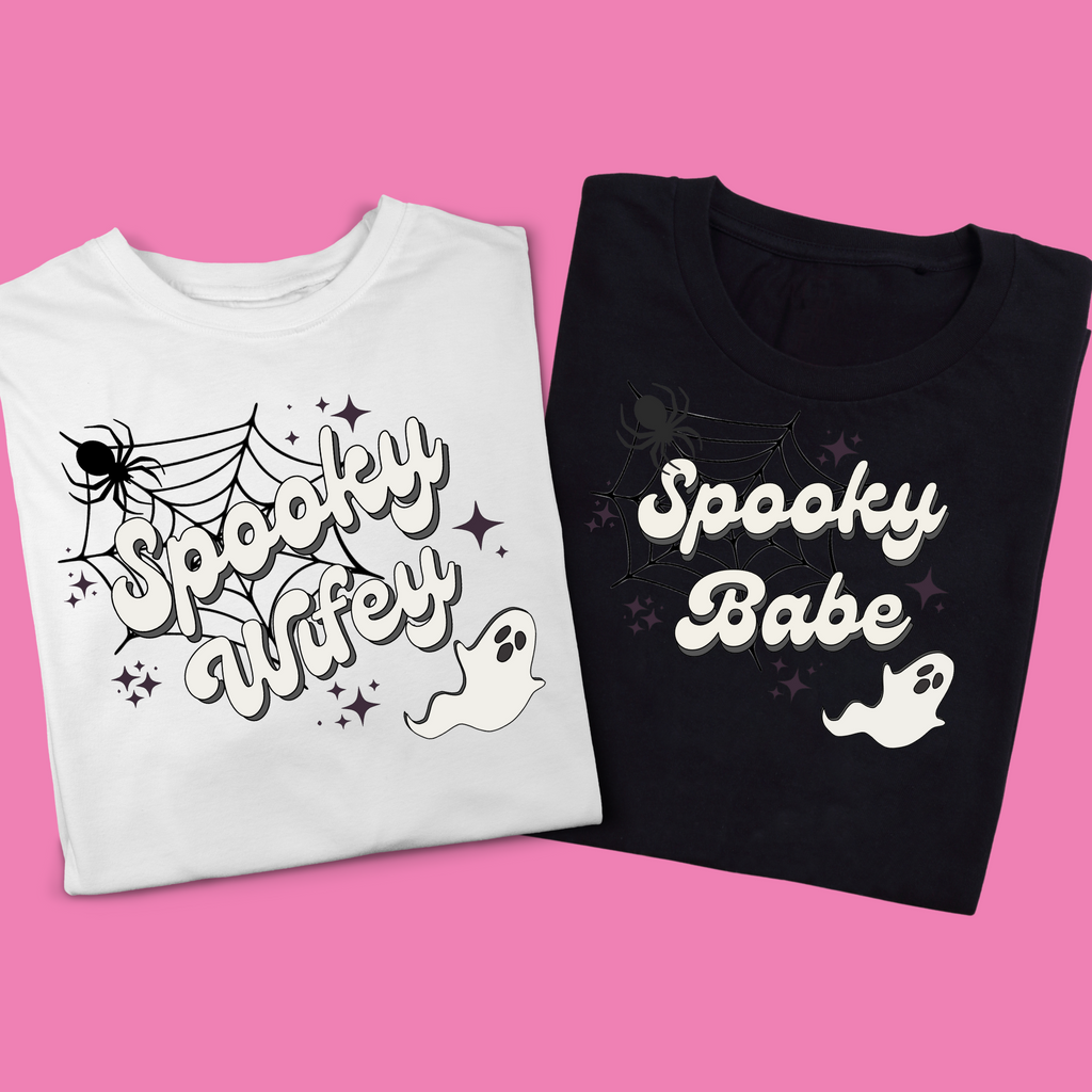 Two t shirts on a pink background. A white shirt with "spooky wifey" printed, and a black t shirt with "spooky babe" shirts. Perfect for the halloween bachelorette!