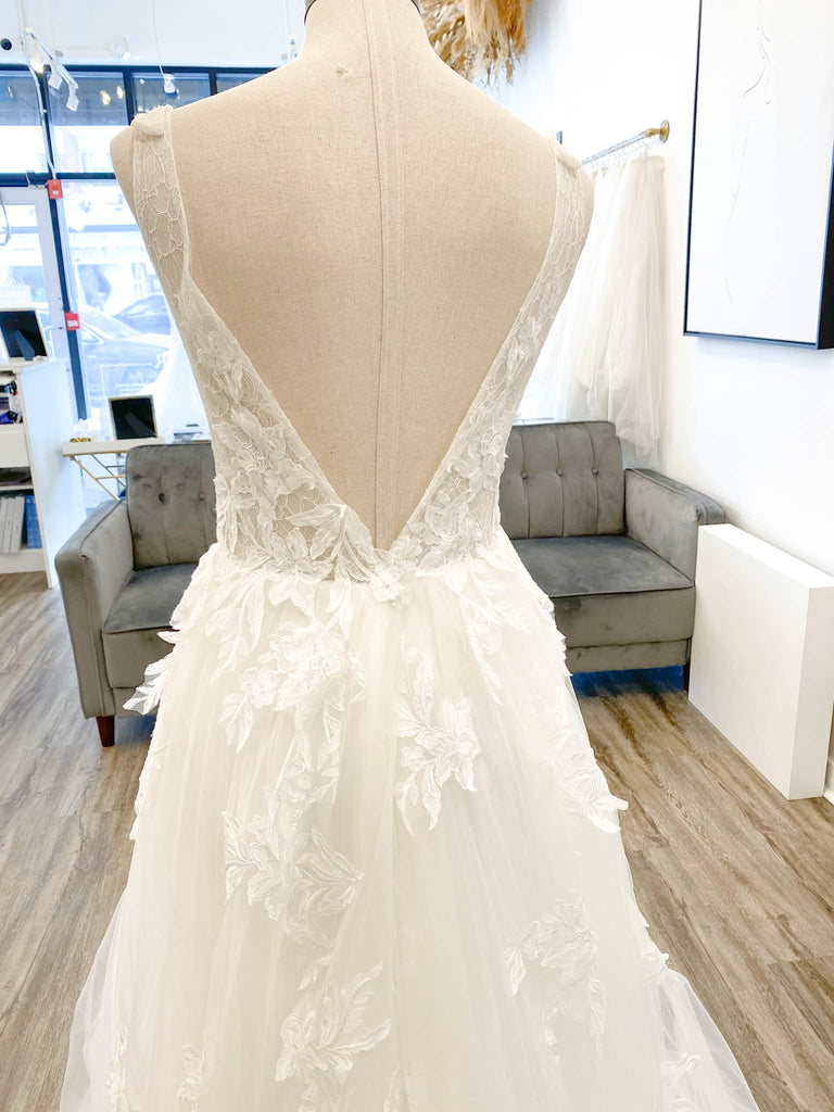 The Giuletta gown is a flirty A-line number featuring stunning lace applique detail adorned throughout the bodice and tulle skirt and a flirty side slit for the subtlest sexy touch.