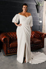 Plus size model wearing Kim an off the shoulder puffy sleeved gown made of draped crepe.