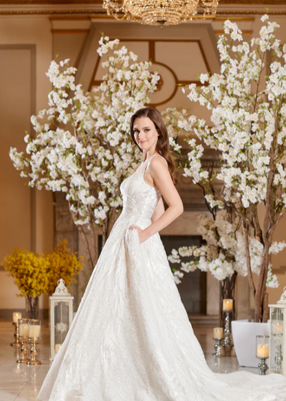 Model wearing Bella by Icon Bridal - a fully beaded ball gown wedding dress, full body side view