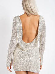 The back view of A young woman wearing a sparkly longsleeve mini dress with a cowl back.