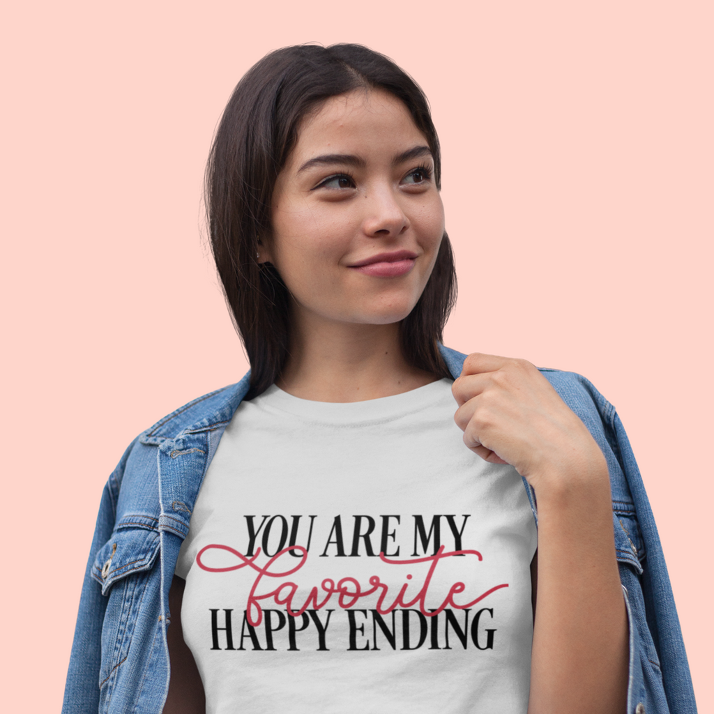 A young woman wearing a white t shirt with "you are my favorite happy ending" written in black and red.